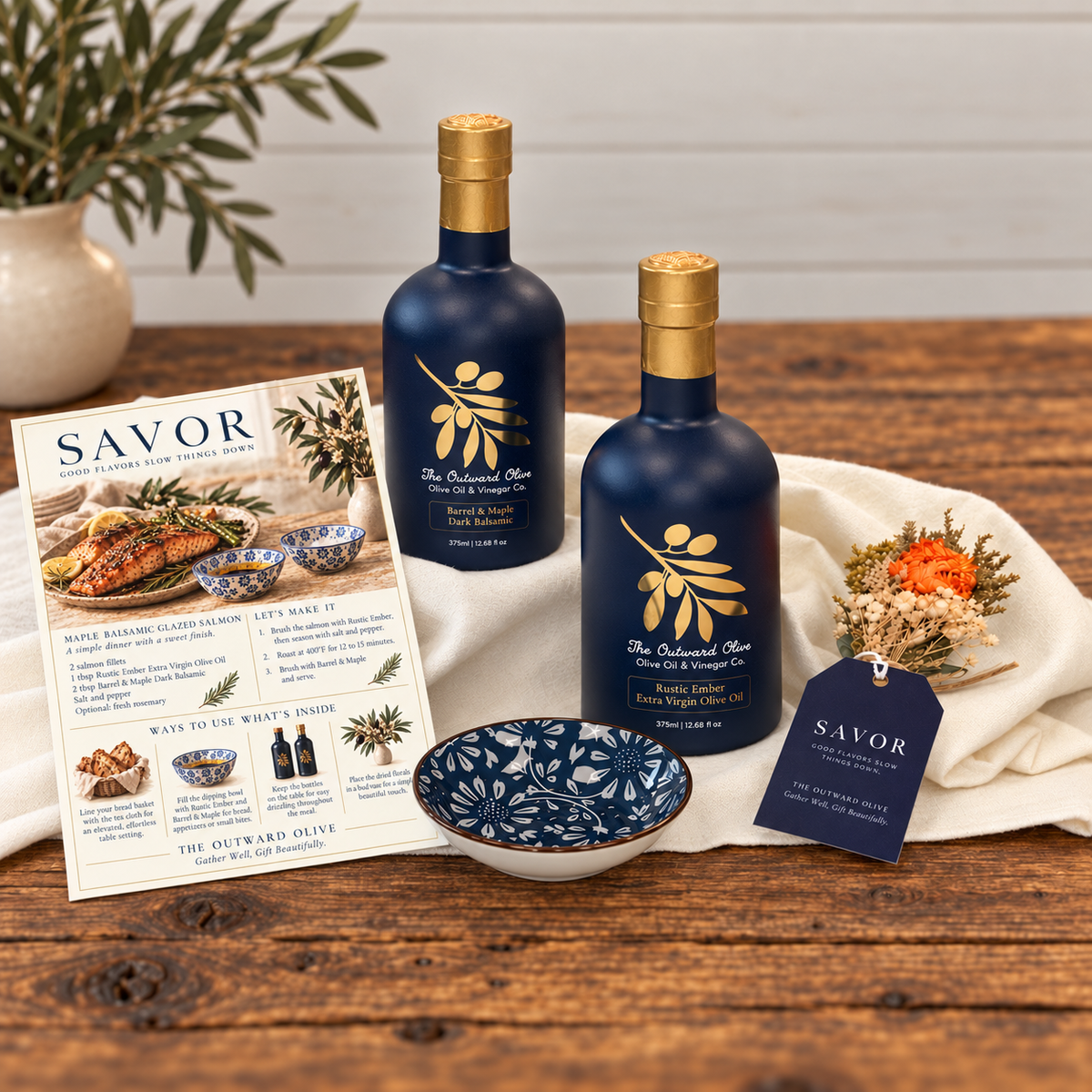 Rustic Ember Extra Virgin Olive Oil and Barrel & Maple Dark Balsamic with a blue and white dipping bowl and recipe card